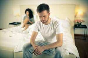 Man sitting on bed concerned about erectile dysfunction and TRT