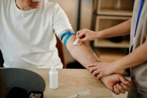 Nurse drawing a blood sample from an older man to investigate low testosterone and anemia